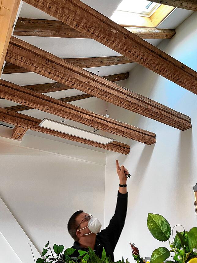 Architekt Hansen zeigt auf die historischen Balken im Dachgeschoss in einem Vereinsraum, per Eisstrahlung gereinigt wurden.