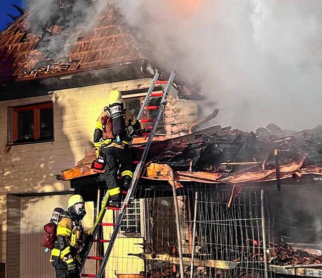 Zwei Feuerwehrleute mit Atemschutzgeräten auf einer Tragleiter.