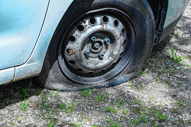 Ist das der Grund für den Parkplatzaufenthalt? Der rechte Vorderreifen des Kleinwagens ist platt.