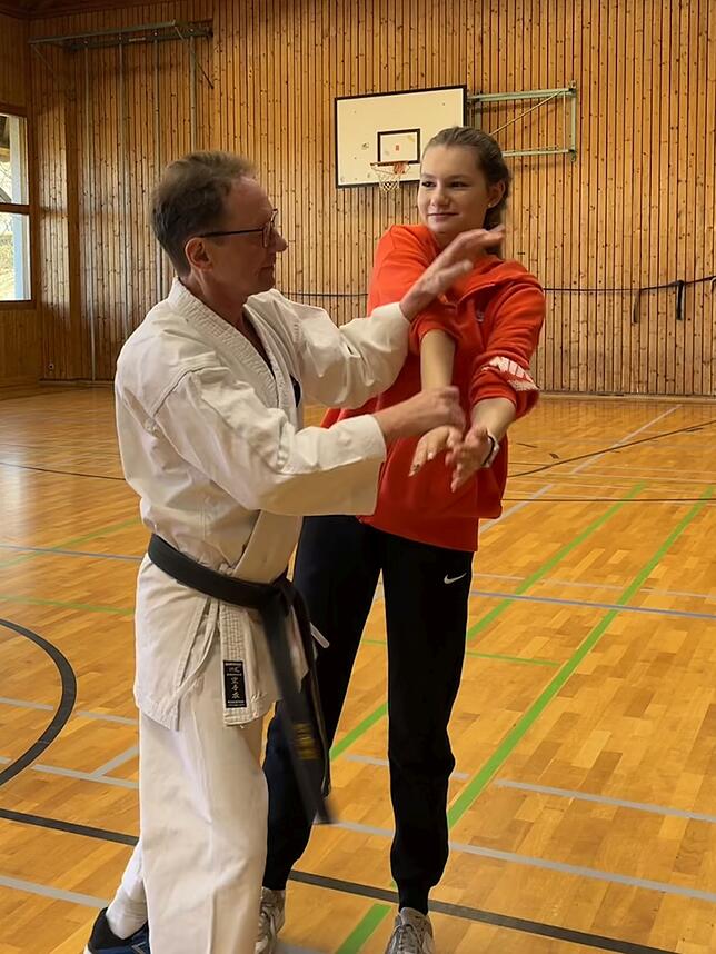 Trainer Siegfried Forster führt das Lösen eines Griffes anhand einer Drehung vor.