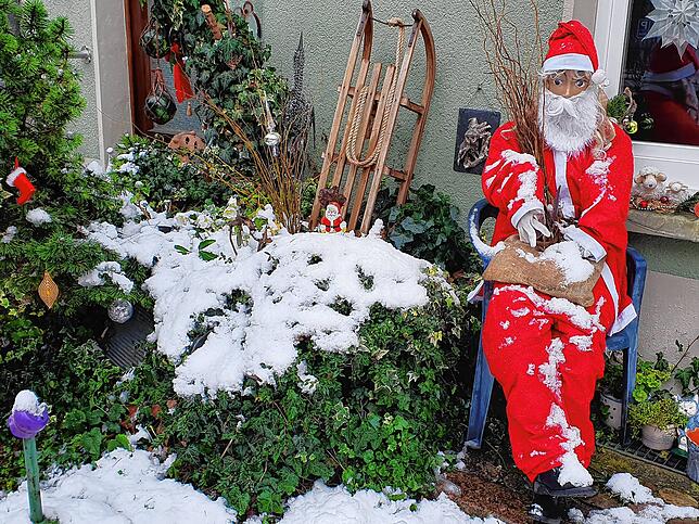 Der Schnee rückt diese Dekoration mit Weihnachtsmann und Schlitten stilecht in Szene.