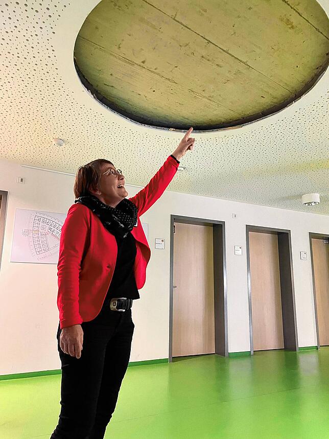 Claudia Vallentin zeigt im zweiten Stockwerk an die Decke, wo sich vor dem Erweiterungsbau ein Fenster befand.