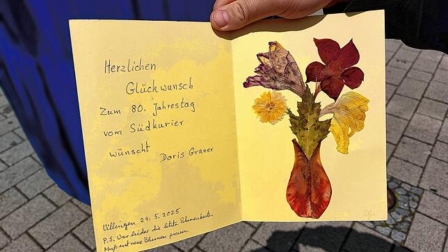 Die SÜDKURIER-Leserin Doris Graner gibt eine mit Blütenblättern verzierte Glückwunschkarte für das Redaktionsteam am Stand ab.
