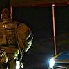 Ein Beamter des Spezialeinsatzkommandos (SEK) ist hinter einem gepanzerten Polizeiwagen gedeckt.