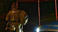 Ein Beamter des Spezialeinsatzkommandos (SEK) ist hinter einem gepanzerten Polizeiwagen gedeckt.