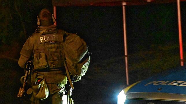 Ein Beamter des Spezialeinsatzkommandos (SEK) ist hinter einem gepanzerten Polizeiwagen gedeckt.