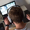 Ein junger Mann sitzt mit einem Headset vor einem Laptop und spielt ein Online-Computerspiel. Bis in die Nacht sitzen Jungs am Computer ...