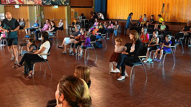 Mit großem Abstand sitzen Kinder und Erwachsene in der Stadthalle und lauschen der Musik.