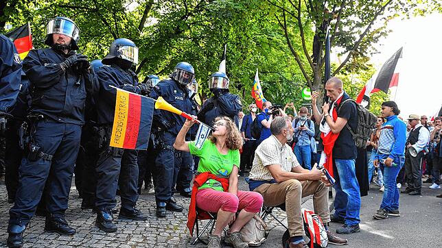 Eine Demonstrantin bläst in eine Vuvuzela vor einer Polizeikette.