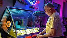 Ralf Meixner sucht an einer „Seeburger“ Titel aus. 50 Singles mit je zwei Oldies darauf, also 100 Titel, stehen zur Auswahl.