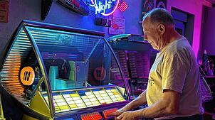 Ralf Meixner sucht an einer „Seeburger“ Titel aus. 50 Singles mit je zwei Oldies darauf, also 100 Titel, stehen zur Auswahl.
