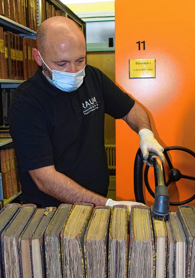 Matthias Raum saugt Staub ab. Der Unterschied zwischen den Büchern ist direkt sehr klar sichtbar.