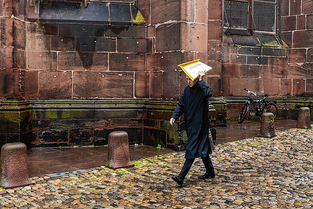 Kurienerzbischof Georg Gänswein geht vor einer Eucharistiefeier bei Regen zur Sakristei des Freiburger Münster.