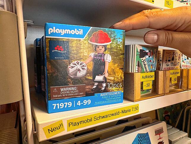 Eine Angestellte nimmt im Freiburger Spielzeugladen Holzpferd die Playmobil-Sonderfigur „Schwarzwald Marie“ aus einem Regal.