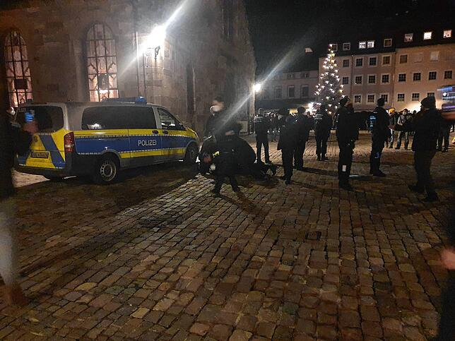 Der Moment der Festnahme: Neben dem reechten Vorderrad des Einsatzwagens halten mehrere Polizisten einen Mann am Boden, der laut und gut ...