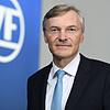 Wolf-Henning Scheider steht im ZF-Forum in Friedrichshafen neben einem ZF-Logo. Er zieht sich von der Konzernspitze zurück.