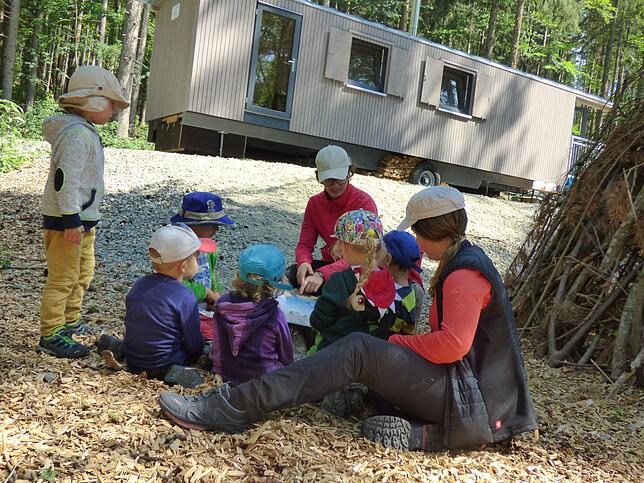 Mütze tragen ist Pflicht im Waldkindergarten – hier schauen sich die Kinder gemeinsam mit den Erzieherinnen Franziska Nusser und ...