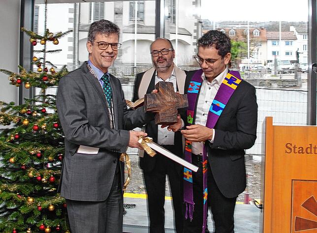 Geschenk der beiden Kirchen: Ein von dem Friedrichshafener Künstler Thomas Rösler geschaffenes Holzkreuz überreichten die Pfarrer Tibor ...