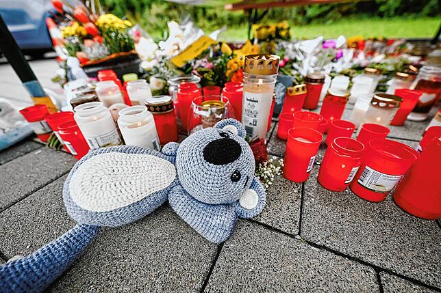 Blumen und Kerzen liegen auf einem Parkplatz eines Supermarktes in der Criesbacher Straße.