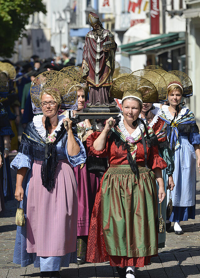 Trachtenträgerinnen tragen die Figur eines Bischofs durch die Straßen von Radolfzell.