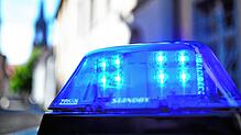 Ein Polizeiauto mit blinkendem Blaulicht steht vor einem Gebäude.