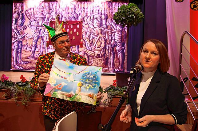 Pritschenmeister Helmut Lempp und Künstlerin Sybille Trefflich bei der Präsentation des Narrenbuch-Titelblatts. Es zeigt eine ...