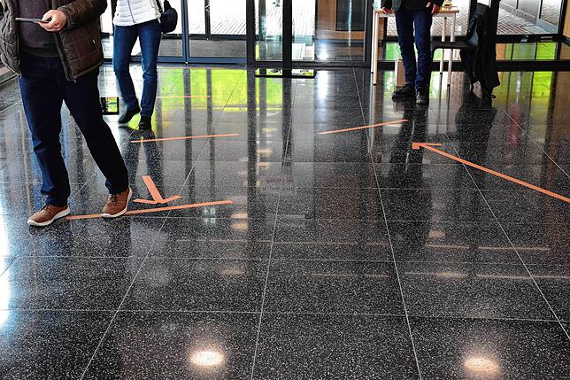 Auf dem Fußboden im Rathaus sind die Abstände und die Laufrichtungen markiert. Trotz der Maßnahmen gehen viele Bürger zum Wählen.