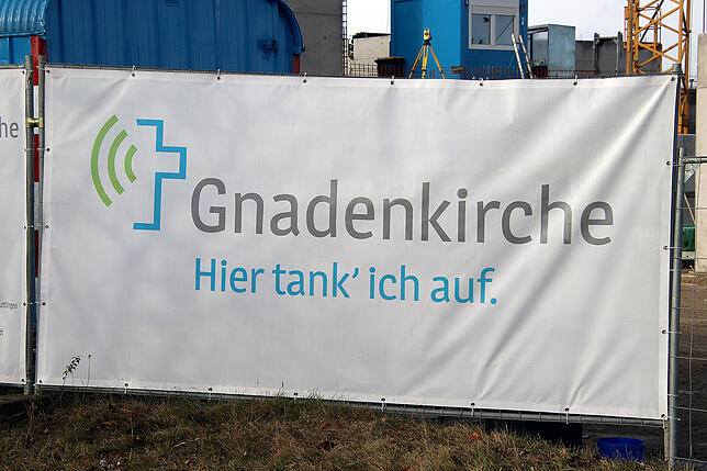 Ein großes Schild am Baustellenzaun verrät, was hier gebaut wird.