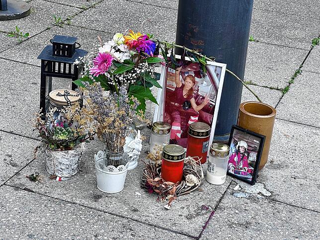 Auch im Sommer 2024 stehen vor dem Klinikum noch Bilder der verstorbenen Oberärztin, Blumen und Kerzen.