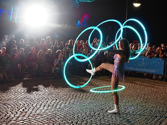 Shia Philipson zeigt ihre Hula-Hoop-Show nach dem Regen auf der Rheinbrücke.