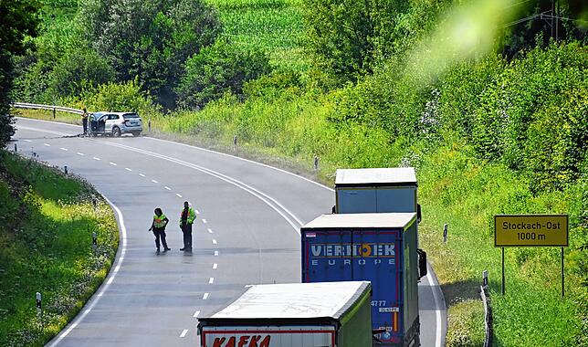Die Lastwagen müssen warten und können nicht weiterfahren. Ein Stück vor ihnen liegt eines der Unfallautos.
