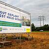 Ein Plakat weist auf den hier geplanten Gesundheitspark und das zukünftige Zentralkrankenhaus hin. Im Hintergrund ist die B 34 zu sehen.