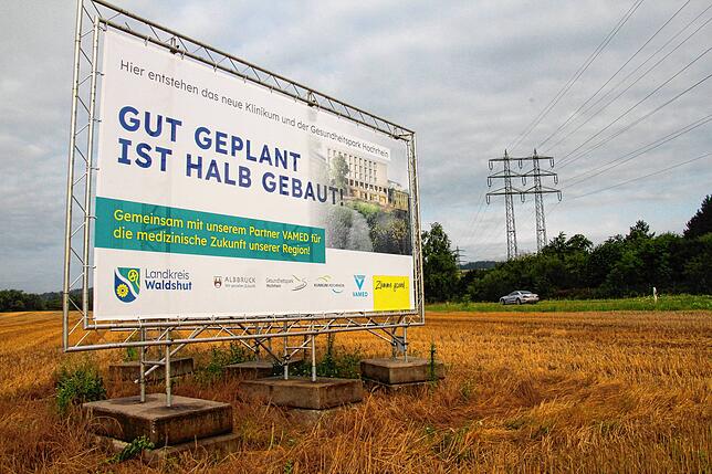 Ein Plakat weist auf den hier geplanten Gesundheitspark und das zukünftige Zentralkrankenhaus hin. Im Hintergrund ist die B 34 zu sehen.