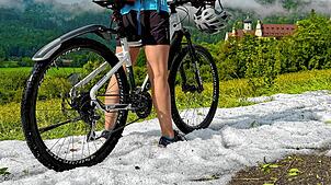 Eine Radfahrerin stellt sich auf dem Donau-Radweg nach einem Unwetter für ein Erinnerungsfoto mit ihrem Fahrrad in den Hagel am Boden. ...