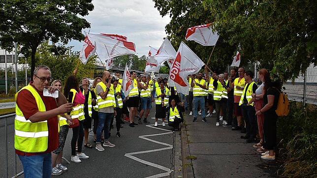 Streikende Mitarbeiter der Hügli stehen vor dem Betriebs-Gebäude. Sie wollen mehr Lohn.