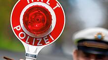 Ein Polizist zieht ein Fahrzeug mit seiner Kelle aus dem Verkehr (Symbolbild).