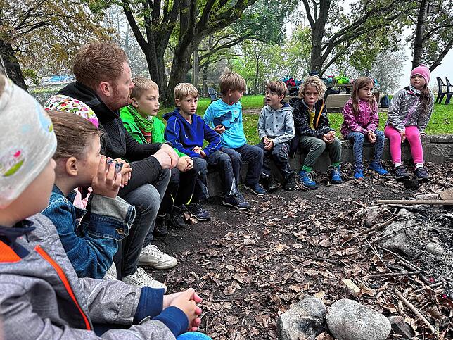 Schüler der FU 7a der Bodensee-Schule sitzen mit ihrem Lehrer Lukas Wachter im Sitzkreis an der Grillstelle. Heute ist Lernen draußen ...