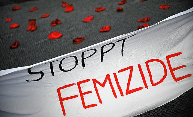 Ein Banner mit der Aufschrift “Stoppt Femizide„ hängt vor roten Schuhen. Laut der NGO UN Women Deutschland e.V. starb 2023 fast jeden ...