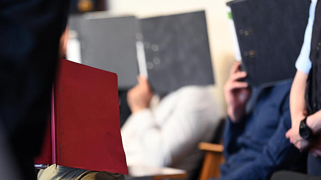 Einige der Angeklagten bedecken ihre Gesichter mit Aktenordnern. Sie sollen im Oktober 2018 eine 18-Jährige neben einer Disco im ...