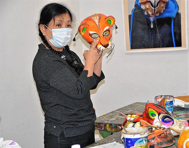 Kursleiterin Chin-Lin Lu-Rauscher erklärt an einer fertigen Maske, wie die Augen und Ohren schattiert werden müssen, damit sie ...