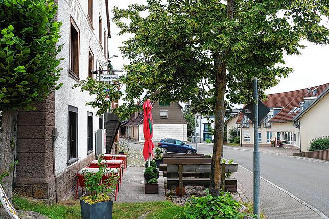 Adé Außenbewirtung. Vor dem Gebäude sind Stellplätze im Gespräch.