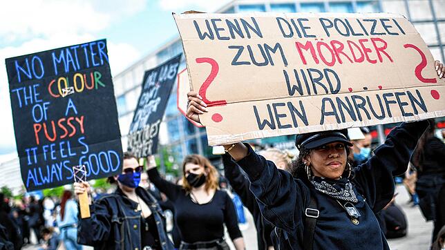 Teilnehmer einer Kundgebung auf dem Alexanderplatz protestieren gegen Rassismus und Polizeigewalt und halten Schilder mit der Aufschrift ...