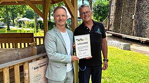 Markus Spettel (links) und Klaus Lang präsentieren im Kurpark stolz die Urkunde zur Auszeichnung „Heilklimatischer Kurort ...