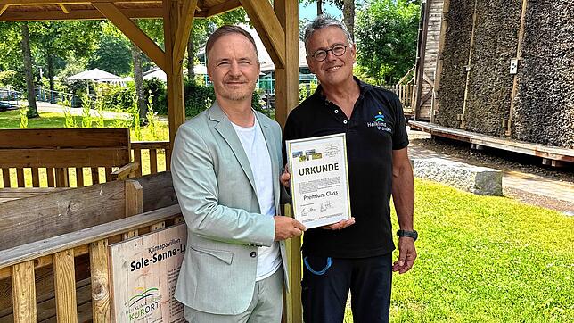 Markus Spettel (links) und Klaus Lang präsentieren im Kurpark stolz die Urkunde zur Auszeichnung „Heilklimatischer Kurort ...