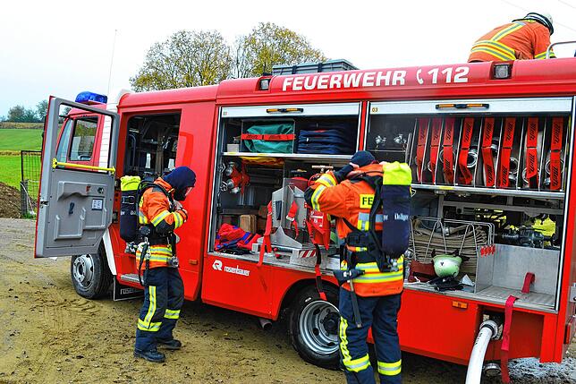 Wehrmänner vom Atemschutz machen sich vor der LF 8/6 für ihren Einsatz bereit.