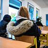 Eine Schülerin sitzt mit einer Winterjacke im Klassenraum (Symbolbild).
