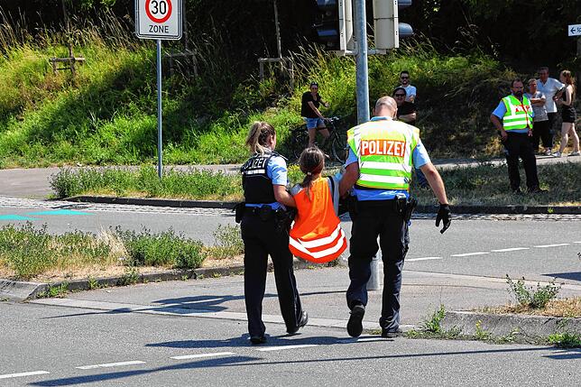 Und auch diese Teilnehmerin an der Klimakleber-Aktion wird von Polizisten weggetragen.