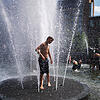 Menschen kühlen sich an einem Brunnen. Mit Temperaturen von über 38 Grad meldet sich der Hochsommer in Deutschland zurück.