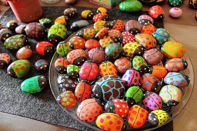 Steine als bunte Glückskäfer bringen gute Laune. Zwischen dem Auftragen müssen die unterschiedlichen Farben trocknen.