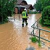 Ein Feuerwehrmann läuft am Montag durch das Wasser des übergelaufenen Dorfbaches.